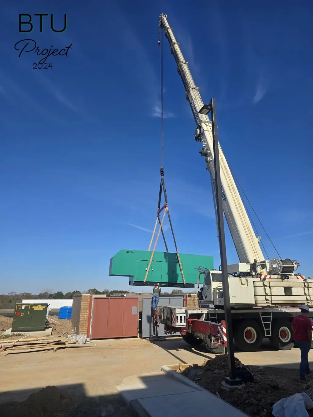 Crane setting a large electrical unit onto its pad on the BTU project, 2024