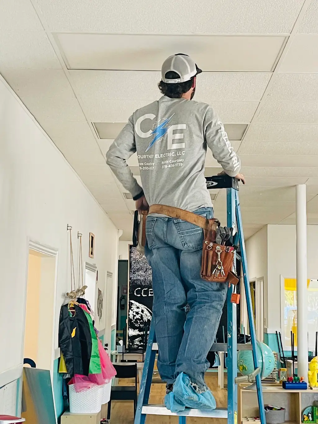 CC Electric electrician working overhead in a school corridor