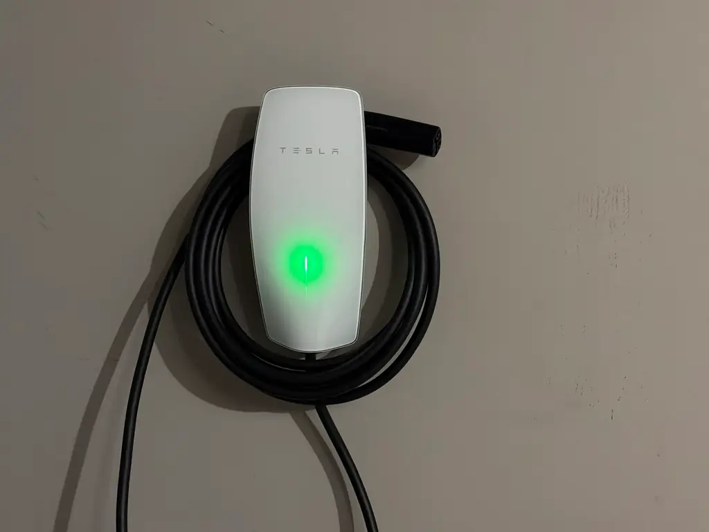 Tesla wall connector installed and coiled on a garage wall